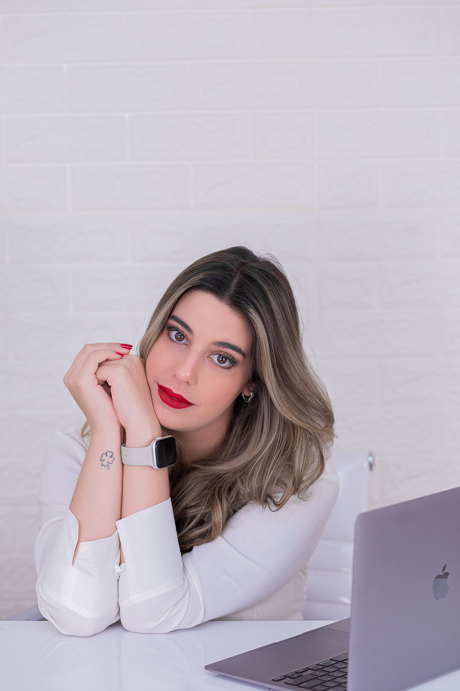 Leticia Teixeira sentada à mesa, com o rosto apoiado nas mãos